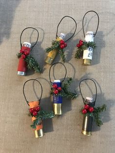 six christmas bells with holly and red berries hanging from them on a tablecloth covered surface