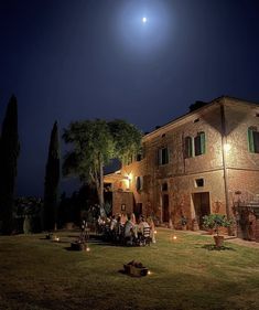 a group of people sitting around a table in front of a large building at night