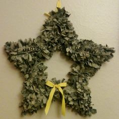 a star shaped wreath hanging on the wall next to a white wall with yellow ribbon