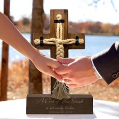 two people holding hands in front of a cross