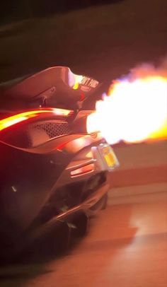 a close up of a motorcycle with flames coming out of it's back end