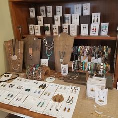 the table is full of jewelry and cards on display for people to see them in