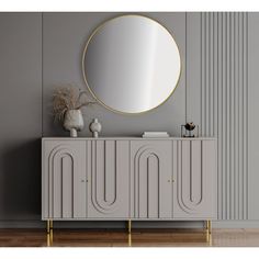 a white and gold sideboard with a round mirror on it's face, against a gray wall