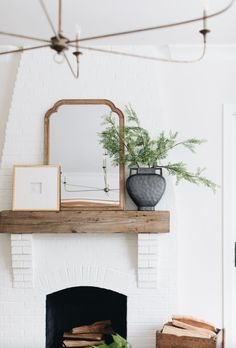 a living room with a fireplace, mirror and potted plant