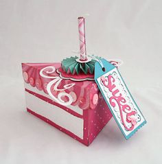 a pink and white box with a birthday candle in it