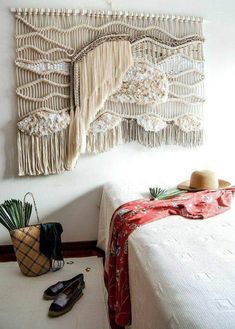 a white bed topped with a wooden table next to a wall hanging