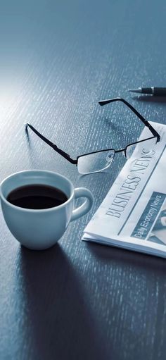 a cup of coffee sitting on top of a table next to a pair of glasses