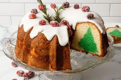 a bundt cake with white icing and cranberry toppings on a glass platter