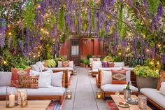 an outdoor seating area with wistery trees and flowers on the ceiling, surrounded by white couches