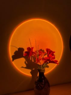 a vase with some flowers in it sitting on a table next to a round light