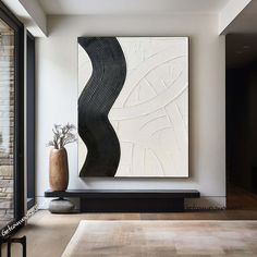 a large abstract painting on the wall in a living room with wooden flooring and white walls