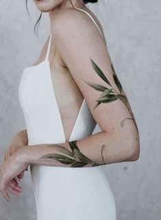 a woman with tattoos on her arms and shoulder is posing for the camera while wearing a white dress