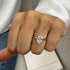 a close up of a person's hand with a diamond ring on their finger