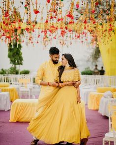 a man and woman in yellow outfits standing next to each other under chandelier