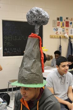 a boy wearing a paper mache hat with a rock on it's head