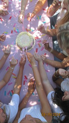 a group of people standing around a cake with sprinkles on it's surface