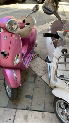 a pink scooter parked next to a white moped