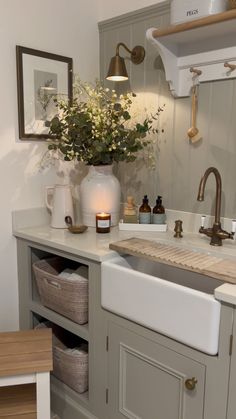 a white sink sitting under a window next to a counter top with flowers in it