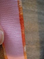 a person is stitching an orange and pink ribbon