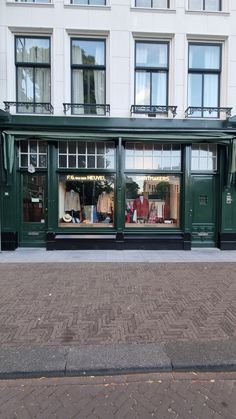 a store front with the windows open on a brick sidewalk in front of an apartment building