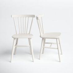 two white chairs sitting next to each other on a white surface with one chair facing the other