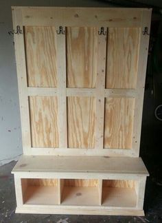 an unfinished wooden bench with three doors on the front and two shelves in the back