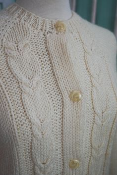 A classic women's cardigan sweater, in a soft ivory white acrylic. It has a unique wide pattern of traditional cable knit down the front. It closes up the front with a row of really unique swirly plastic buttons. The sweater is soft and comfy, not stiff at all. No damage or issues. Please check measurements carefully. Condition: Very Nice Vintage Tag: 100% Acrylic Size L Measurements in inches.... Length: 23.5 Chest: 19 ✩ Because you don't want to miss a thing, follow @heartkeyologie on Facebook Elegant White Cable Knit Cardigan, White Cable Knit Classic Outerwear, Elegant Cream Cable Knit Cardigan, Elegant Cream Cable Knit Outerwear, Fitted Cream Sweater With Buttons, Classic White Sweater With Buttons, Fitted Cream Knitted Sweater, Cream Fitted Knitted Sweater, Classic Beige Cable Knit Cardigan