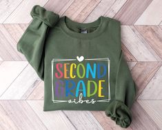 Second Grade Vibes Sweatshirt, Second Grade Teacher Sweatshirt, 2nd Grade Sweater and Hoodie Thank you for visiting our Etsy shop. Take a leisurely stroll through our collection and discover the ideal sweatshirt or hoodie to elevate your style. We are excited about the opportunity to assist you and are committed to delivering a fantastic shopping experience!  HOW TO ORDER YOUR CUSTOM SWEATSHIRT OR HOODIE  1. Explore and meticulously review our captivating collection of photos. 2. Indulge in the pleasure of selecting the perfect hue for your Sweatshirt or Hoodie. 3. Tailor your experience by choosing the ideal size for your Sweatshirt or Hoodie. 4. Effortlessly click "ADD TO CART," providing you the option to either enhance your order with more vibrant colors or proceed seamlessly       to Green Crew Neck Sweatshirt For School, Green Casual Sweatshirt For School, Green Long Sleeve Sweatshirt For School, Green Pre-shrunk Hoodie With Crew Neck, Green Casual Pre-shrunk Hoodie, Green Long Sleeve Tops For School Spirit, Casual Green Pre-shrunk Hoodie, Green Pre-shrunk Crew Neck Hoodie, Teacher 2nd Grade Shirts