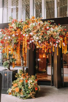 an orange and yellow tree is in the middle of a room with large windows on both sides