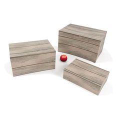 three wooden boxes sitting next to each other on top of a white surface with an apple in the middle