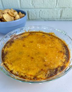 a casserole dish on a table next to a bowl of crackers