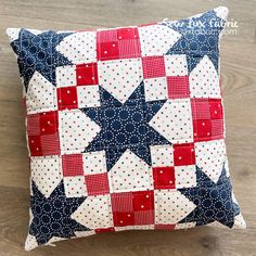 a red, white and blue quilted pillow sitting on top of a wooden floor