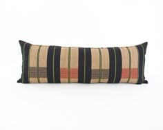 a black and tan striped pillow on a white background with a green stripe down the middle