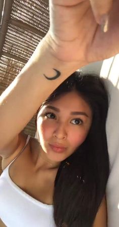 a young woman with a crescent tattoo on her arm and wrist is posing for the camera