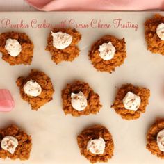 pumpkin cookies with cream cheese frosting are on a baking sheet, ready to be eaten