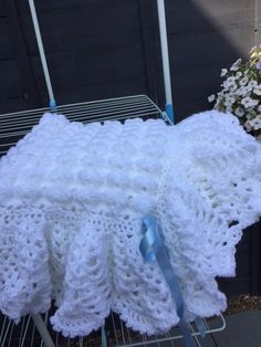 a white crocheted blanket sitting on top of a metal rack next to flowers