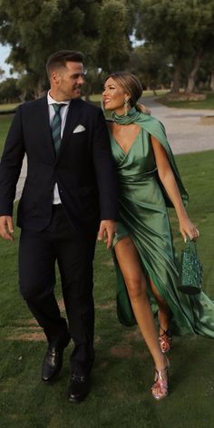 a man and woman dressed in formal wear walking through the grass