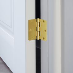 a close up of a door handle on a white door with black trim and gold hardware