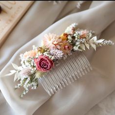 a hair comb with flowers on it sitting on top of a white cloth covered table