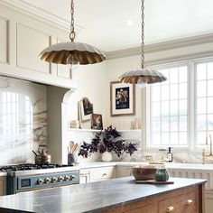 a kitchen with an island and two pendant lights hanging from it's ceiling over the stove