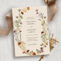 the wedding card is decorated with flowers and leaves, along with a ribbon tied around it