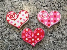 three decorated heart shaped cookies sitting on top of a granite countertop next to each other