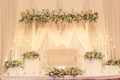 a decorated stage with flowers and candles for a wedding or reception ceremony at the same time