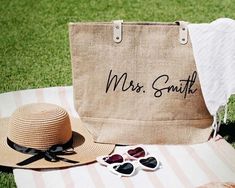 a hat, sunglasses and tote bag sitting on the grass