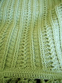 a green crocheted blanket on top of a bed