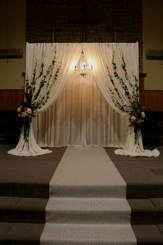 an aisle decorated with flowers and greenery next to a set of steps leading up to the alter