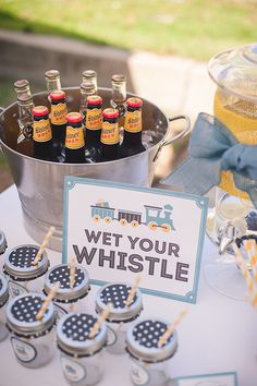 a table topped with lots of bottles of beer next to a metal bucket filled with drinks