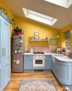 a kitchen with yellow walls, blue cabinets and an area rug on the floor in front of it