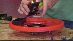 a man is working on an object with a lighter in it's hand and some wires are plugged into the device