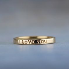 Show her how you feel with this sweet little gold ring.  "I LOVE YOU" is inscribed on this outside of the solid 14k gold ring. It has a smooth finish for a lovely shine.  This ring is ready to ship in a size 5.  If you need a different size, I am happy to make a ring exactly to your specifications. You can find the made to order version of this ring here https://www.etsy.com/listing/99515676.  High quality 1 mm stamps were used to stamp the tiny but readable words on the ring. To see how small the letters are, take a look at a penny. The words "In God we Trust" are the same size. -------------------- About the ring - Handmade from 14k yellow gold. - 2 mm wide (5/64 of an inch) wide - Smooth shiny finish - Inscription outside: I LOVE YOU -------------------- The ring will arrive gift wrappe Hand Stamped 14k Gold Engraved Ring, Hand Stamped 14k Gold Promise Ring Jewelry, Hand Stamped 14k Gold Jewelry For Promise Ring, Engraved 14k Gold Promise Ring, Hand Stamped 14k Gold Wedding Rings, 14k Gold Hand Stamped Wedding Rings, 14k Yellow Gold Hand Stamped Engraved Ring, Hand Stamped 14k Gold Ring, Hand Stamped 14k Yellow Gold Engraved Ring